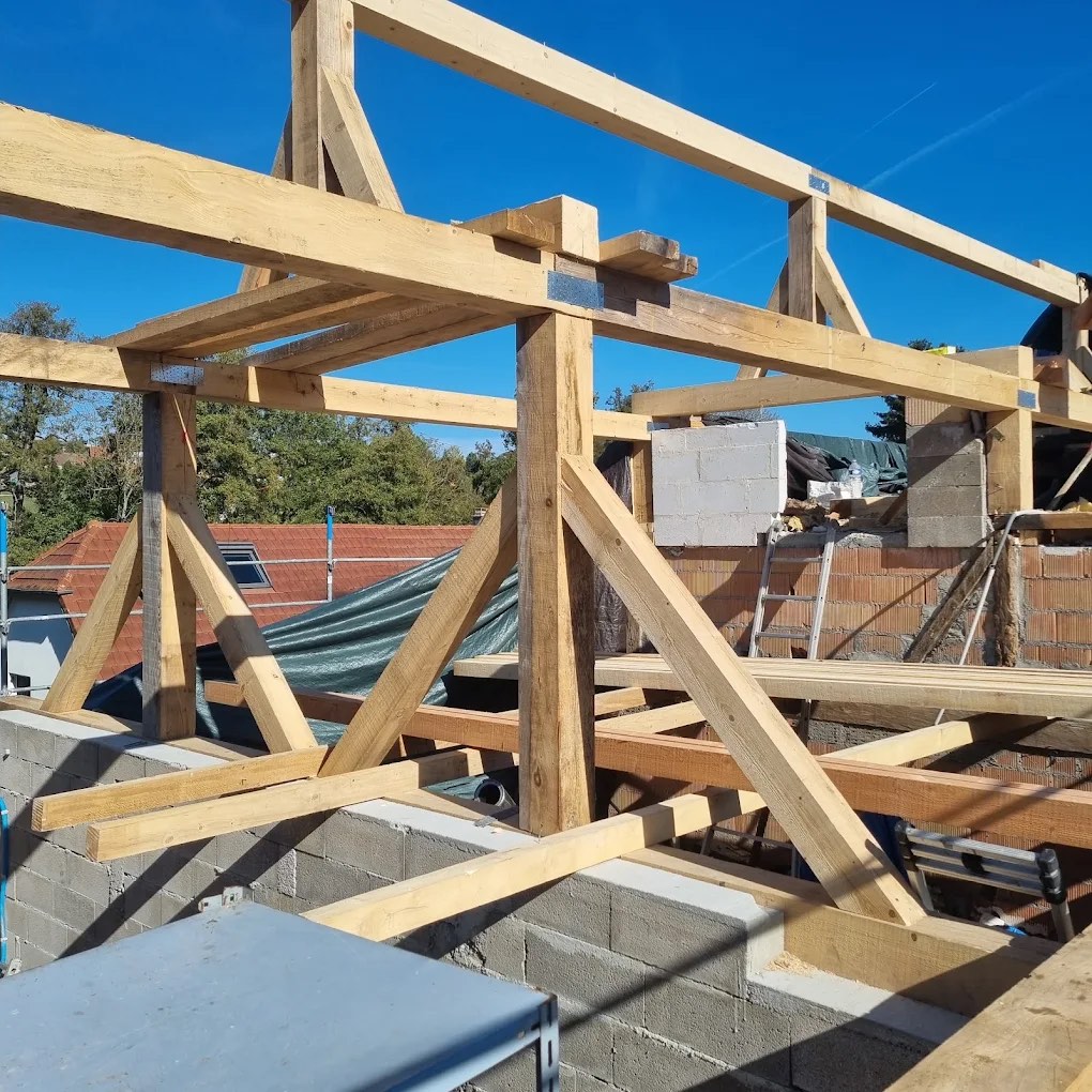 Charpente bois traditionnelle en cours de pose sous un ciel clair